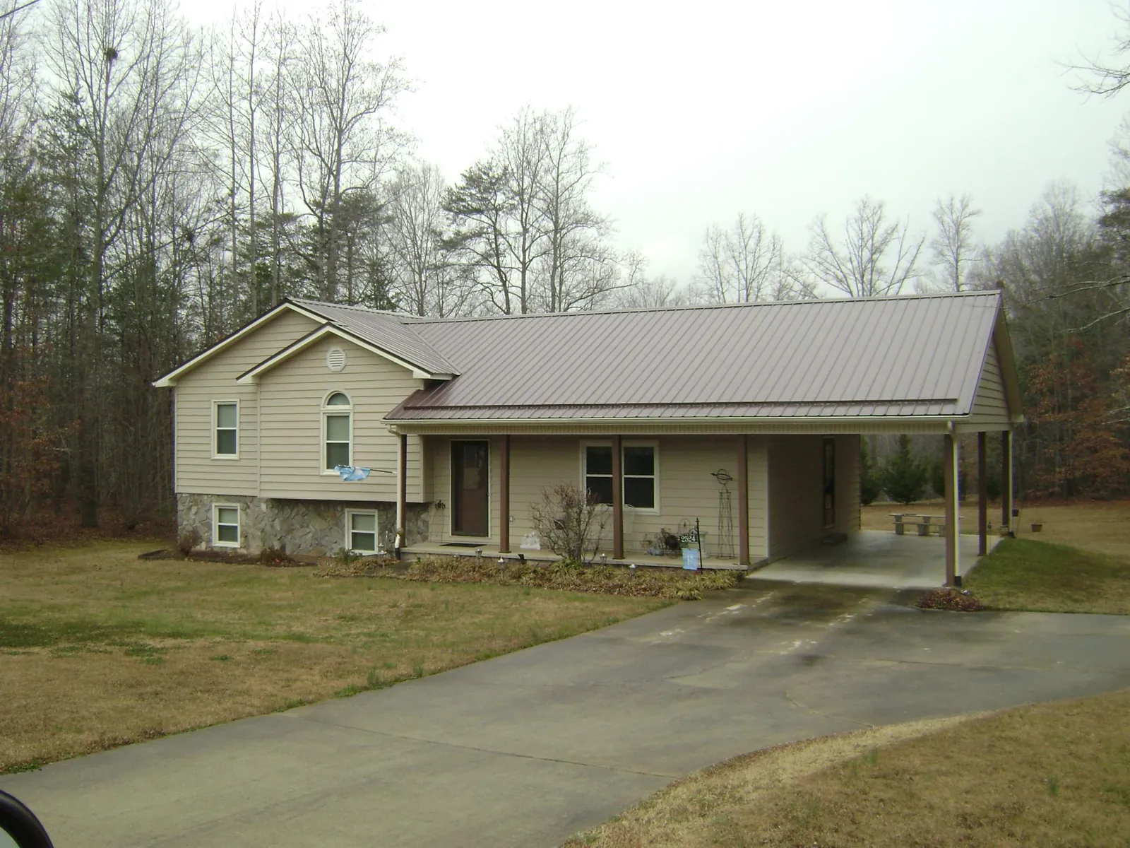 Brown metal roof on a tan split level home with an attached carport in Mount Morris